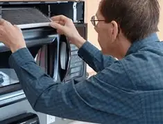Appliance repair technician replacing a microwave vent filter in Dover, DE