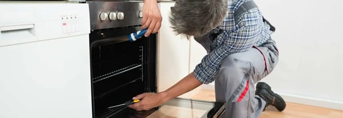 Oven repair technician inspecting and servicing an electric oven in Dover, DE