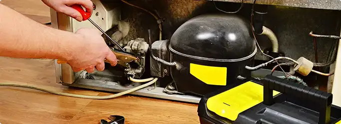 Refrigerator repair technician fixing the compressor and wiring in Dover, DE