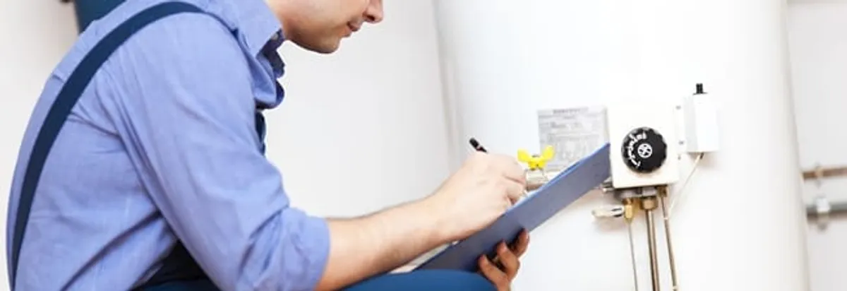 Water heater repair technician inspecting the unit and recording service notes in Dover, DE